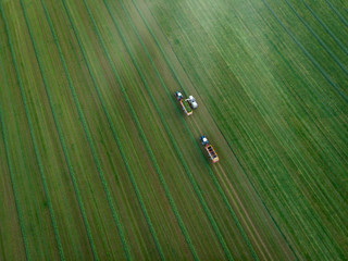 Aerial view of agriculture field with tractors harvesting hay © Peter Maszlen
