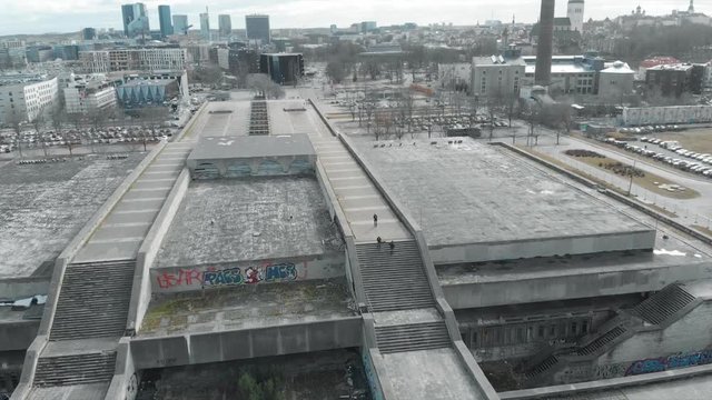 Aerial view of people with guitars descending the stairs of a large grey bridge against blue cloudy sky and city buildings in early spring. Urban architecture