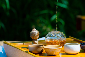 On the table on a wooden tray a teapot with tea, teapot, cups. Man, hands pouring tea
