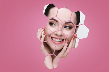 Fototapeta na wymiar Portrait of model with natural nude make up touching her face in pink hexagon frames. Beautiful happy young woman applying moisturizer cream on her perfect glow clean skin.