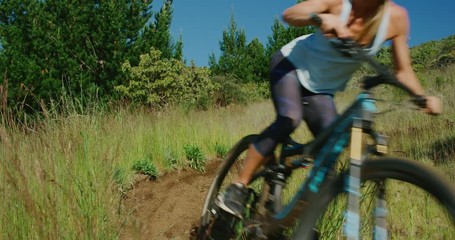 Summer mountain biking adventures, active adventurous woman riding her mountain bike around a berm turn in slow motion