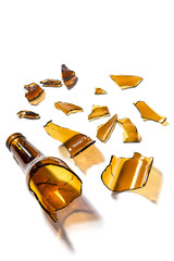 Glass beer bottle broken in half isolated on white background. Opaque glass bottle of brown color broken in pieces and cracked. Improvised weapon.