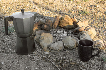 Preparing coffee using a bonfire during a camp in the forest. Bonfire with rocks, coffee maker moka...