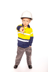 Young blond caucasian boy pointing out, fierce angry look role playing a frustrated construction worker supervisor in a yellow and blue hi-viz shirt, boots, white hard hat, minus hammer and tape