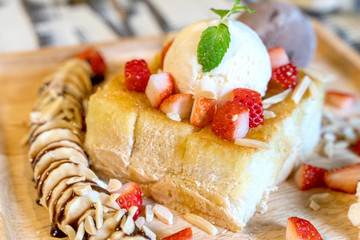 Strawberry honey toast with ice cream on wood plate dish.