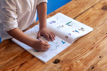 Preschool age child doing the math. Little boy doing homework. Drawing on kid notepad. Free space