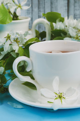 cup of tea with apple petals on a blue background, close-up
