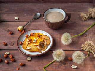 Light fruit chips and peanut nuts for light morning coffee with milk on a wooden rustic tray