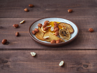 Fruit chips without sugar and additives on a small plate for a healthy snack for people leading a healthy lifestyle