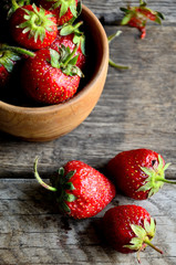 Strawberries in a wooden cup on an old rustic table, top view.