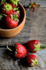 Strawberries in a wooden cup on an old rustic table, top view.