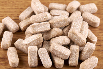 Many brown pills on wooden background. Tablets and medicine
