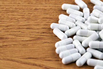 Fototapeta na wymiar Many white capsules on wooden background. Pills and medicine