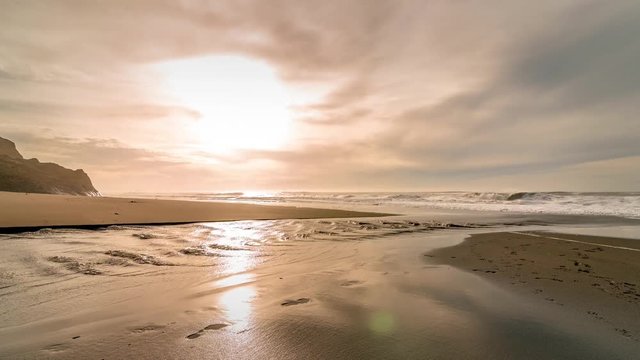 Time-lapse of a creek meeting the ocean on a beach in California at sunset, showing interesting wave patterns