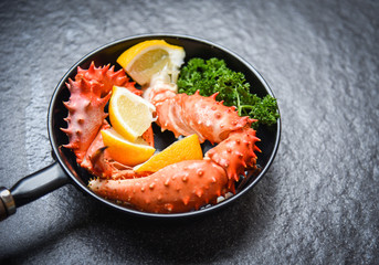 Boiled crab claws cooked seafood pan with Alaskan King Crab with lemon parsley herbs and spices on dark background - red crab hokkaido in a hot pot