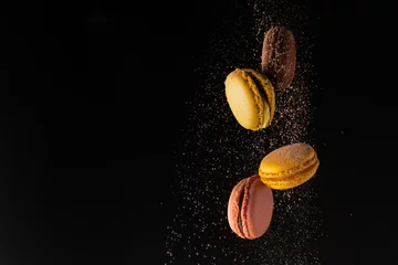 Crédence de cuisine en verre imprimé Macarons Macarons colorés, biscuits français, lévitations colorées avec de la poudre de cacao sur fond noir