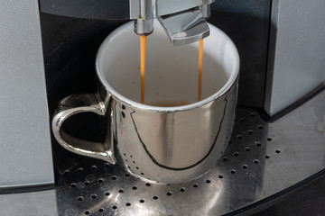 Professional espresso machine pouring fresh coffee into a neat chrome reflective cup