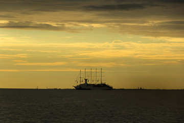 Fototapeta premium Cruise yacht in the Gulf of Finland on a background of golden sky with clouds