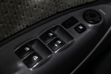 Obraz premium Сlose-up of the car black interior: the side door buttons: window adjustment buttons, door lock and other buttons.
