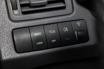 Obraz premium Сlose-up of the car black interior: headlight adjustment buttons, off road 4 WD and other buttons .