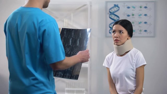 Male surgeon informing female patient in foam cervical collar bad x-ray result