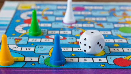 Multi-colored game chips with dice on the playing board. Board game