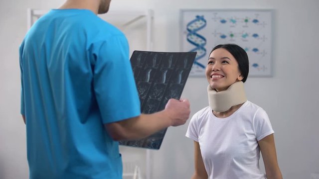 Male doctor informing female patient in foam cervical collar good x-ray result
