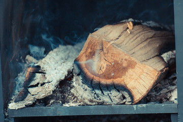 Firewood, carbon and ash in fireplace or smokehouse