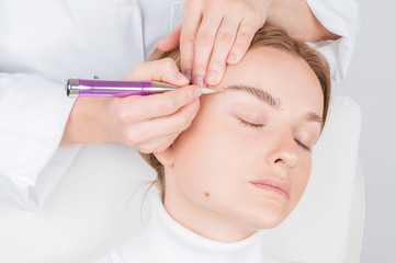 Obraz na płótnie Canvas Microblading eyebrows. Attractive woman getting facial care and permanent makeup.