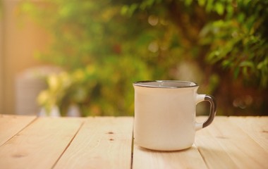 Cup of hot coffee on wooden table in the green garden this morning. 