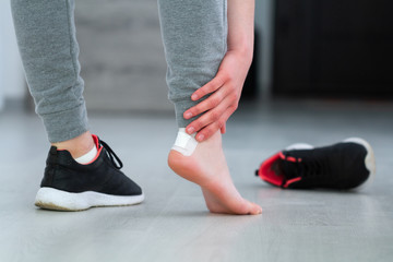 Woman's heel with white medical adhesive plaster from calluses during wearing a new shoe. Skin care...