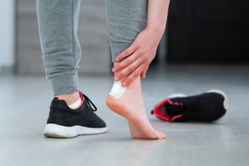 Woman's heel with white medical adhesive plaster from calluses during wearing a new shoe. Skin care...