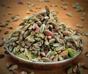 cracked pistachios in a bowl on wooden table