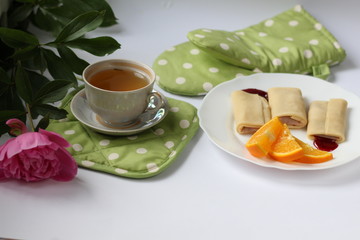 breakfast consisting of pancakes with berries and orange slices and a cup of tea