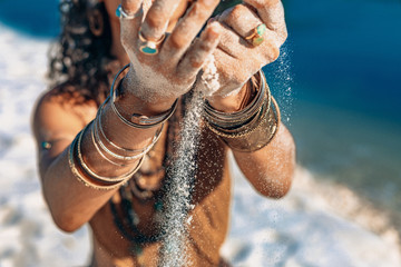 beautiful young woman holding sand in her hands on the beach