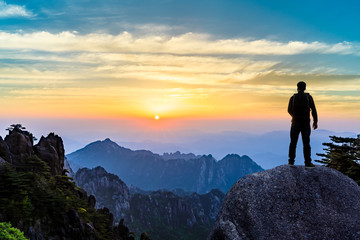 Young happy backpacker on top of a mountain enjoying valley view
