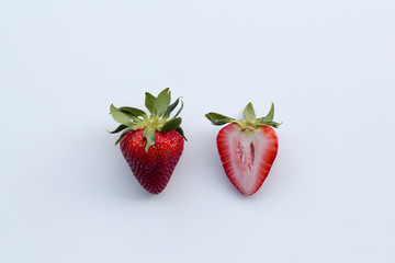 Whole and cross section of fresh strawberries with leaves isolated on white.
