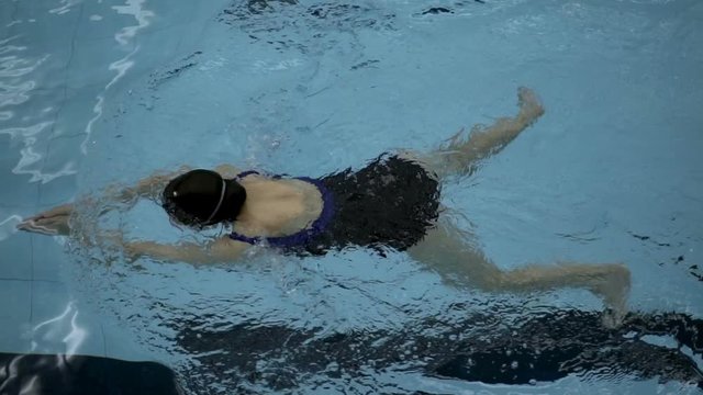 Top view of a female doing breaststroke in swimming pool, steadycam shot