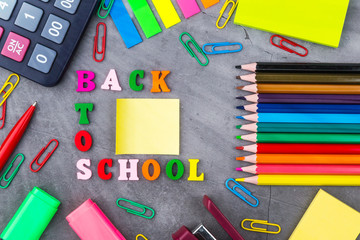 The layout of school supplies on a dark gray background. The view from the top. Flat lay.