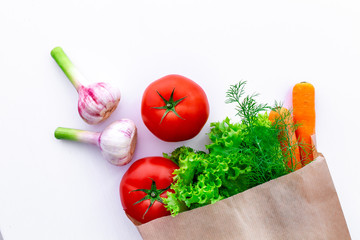 Fresh organic eco vegetables in craft paper bag on white background.