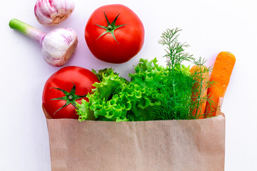 Fresh healthy vegetables in craft paper bag on white background.