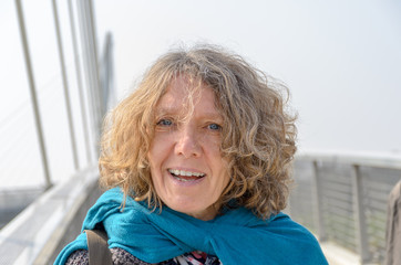 Fototapeta na wymiar Bust portrait of smiling curly woman on bridge