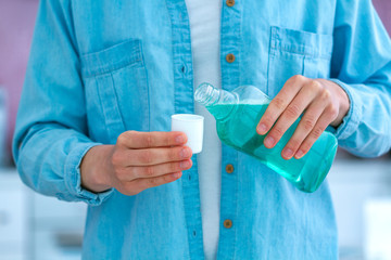 Woman pouring mouthwash gel for rinsing mouth, fresh breath, healthy teeth and gums. Oral hygiene and teeth care.