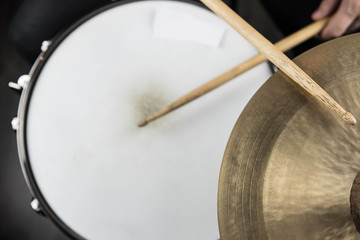 Professional drum set closeup. Man drummer with drumsticks playing drums and cymbals, on black wooden background
