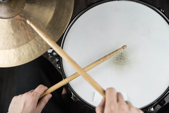 Professional drum set closeup. Man drummer with drumsticks playing drums and cymbals, on black wooden background