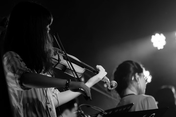 Young Violinist Girl Performance with Her Violin iNstrument on the indoor Concert Stage. Black and White.