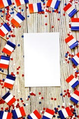 The national holiday of July 14 is a happy Independence Day of France, Bastille Day, the concept of patriotism, memory, place for text, confetti and flags on a wooden table. vertical , mocup