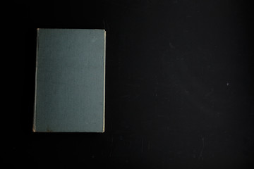 Very old book with a tattered cover on a dirty dark background.