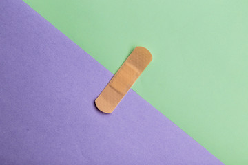 Adhesive bandage or Sticking plaster on a two colored paper background.