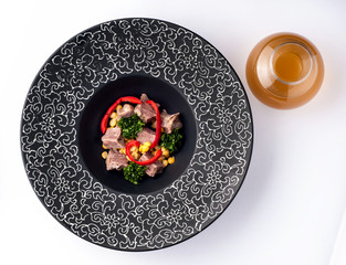A bowl of soup isolated on white background, top view. Black plate with a pattern